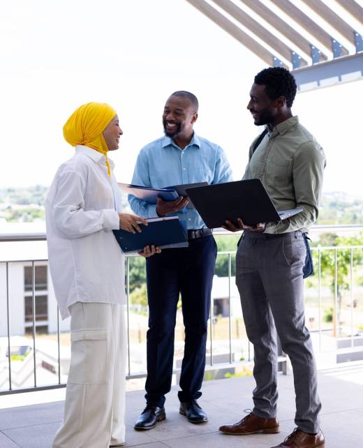 Happy diverse business people discussing and holding documents outside office. Global business, finances and office concept.
