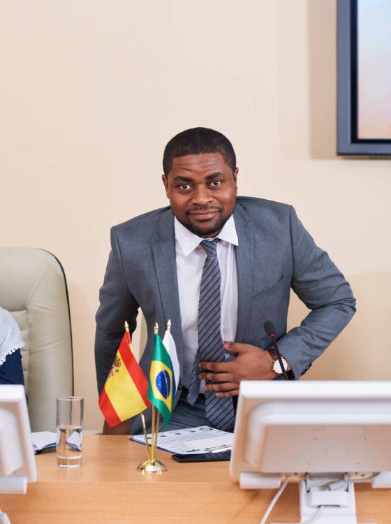 Young confident African-american businessman or delegate in formalwear looking at you while taking seat by table at conference